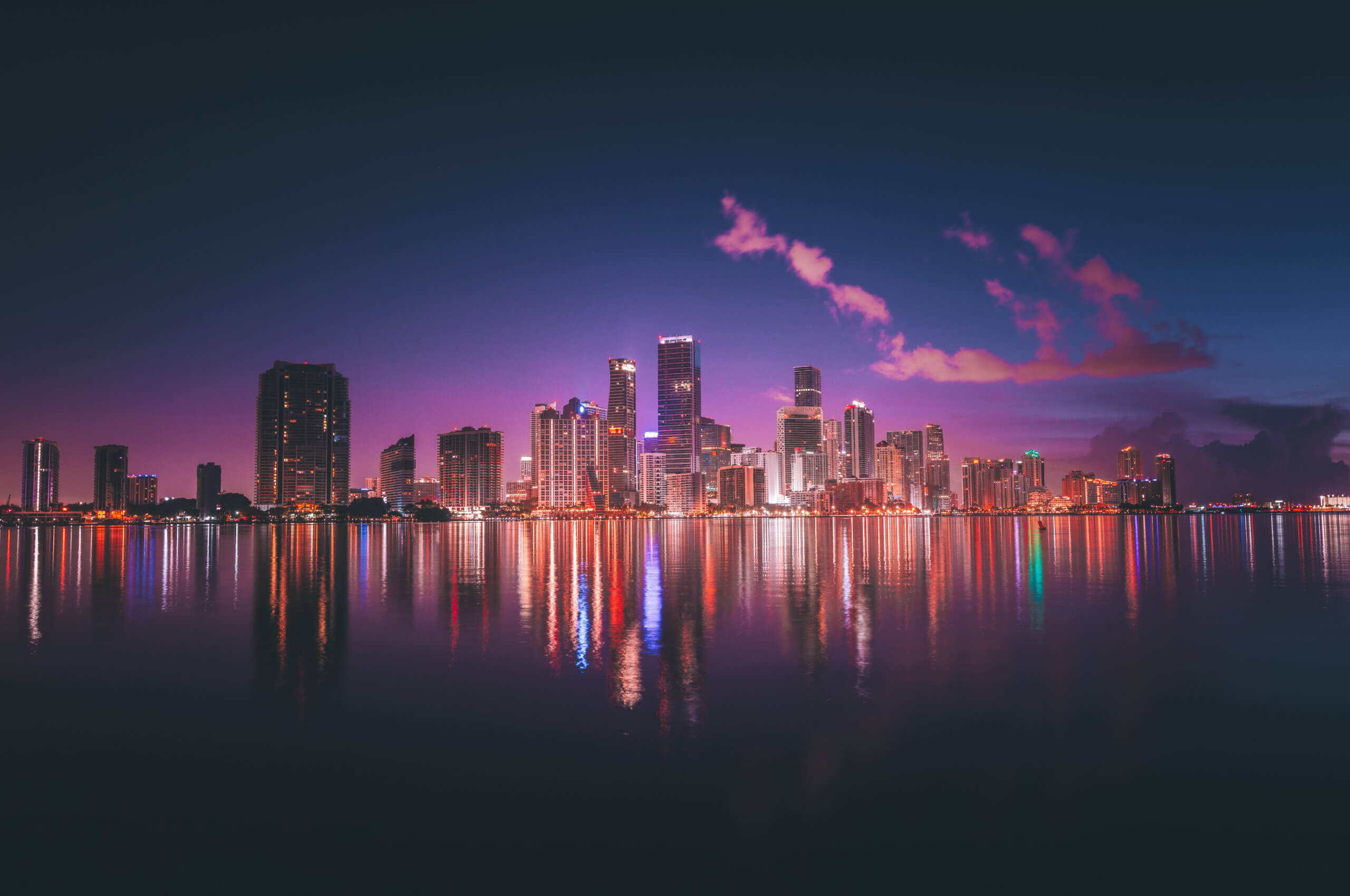 Miami skyline glowing over calm waters.