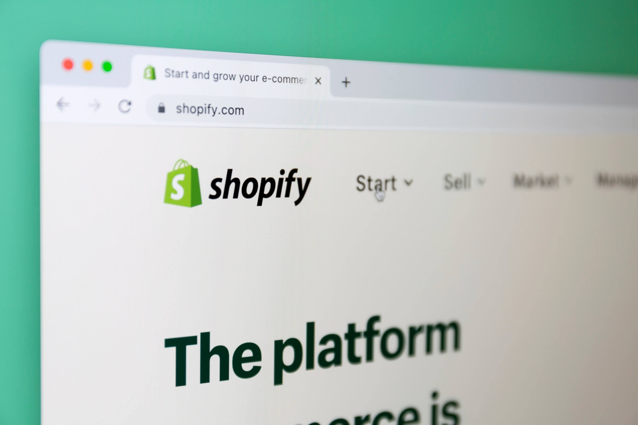 Close-up of a web browser displaying the Shopify homepage, with the Shopify logo and navigation menu visible against a green background.