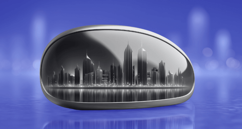 A futuristic silver object resembling a pebble or capsule displays a black-and-white city skyline reflected on its surface, set against a blurred blue background with faint outlines of tall buildings.