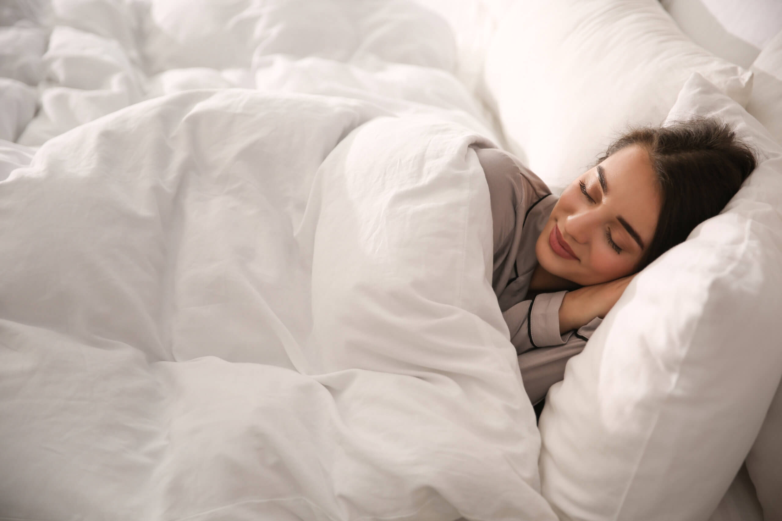Beautiful young woman wrapped with soft blanket sleeping in bed
