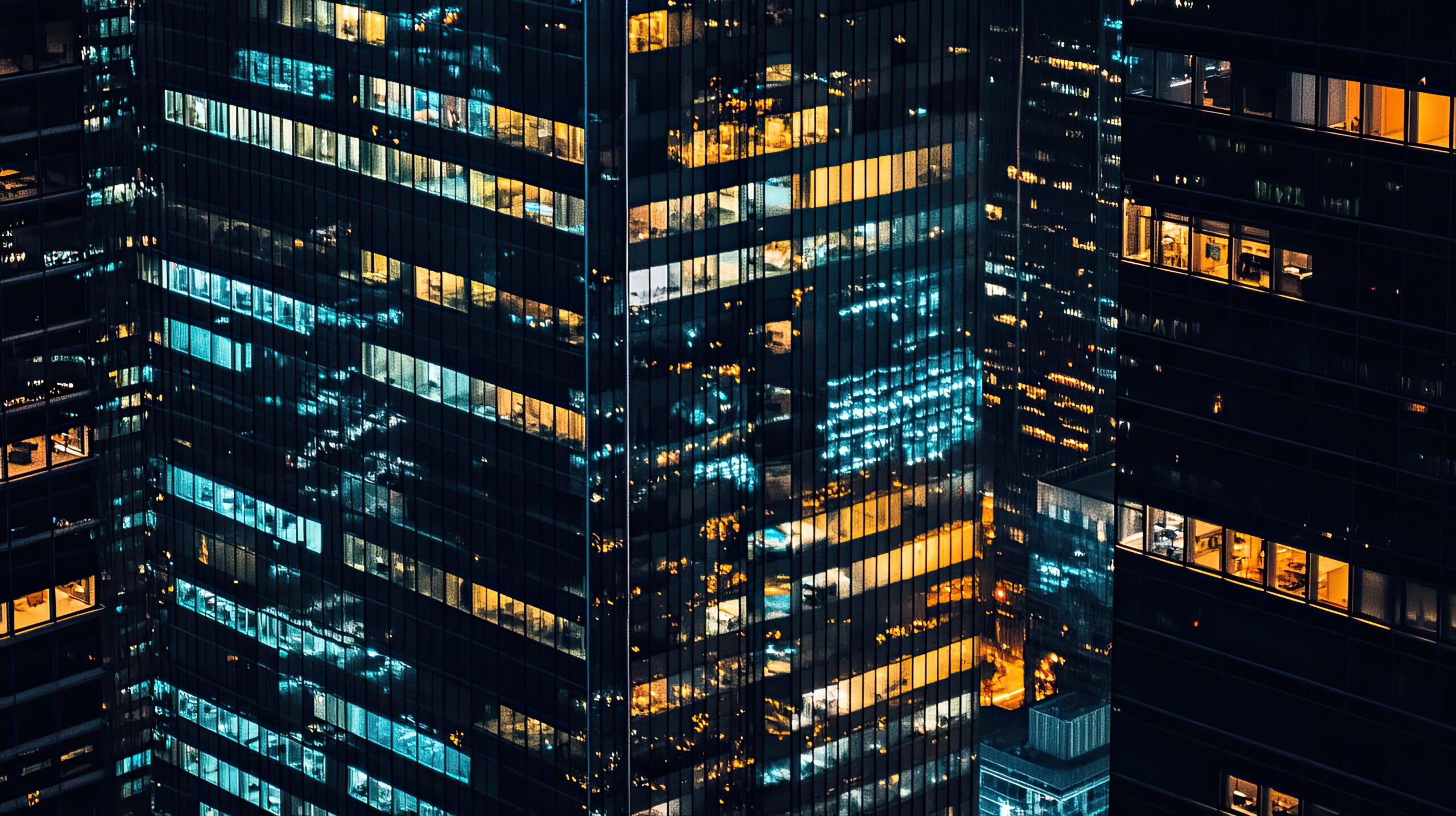 Silhouettes of towering glass office buildings reflecting city lights at night.
