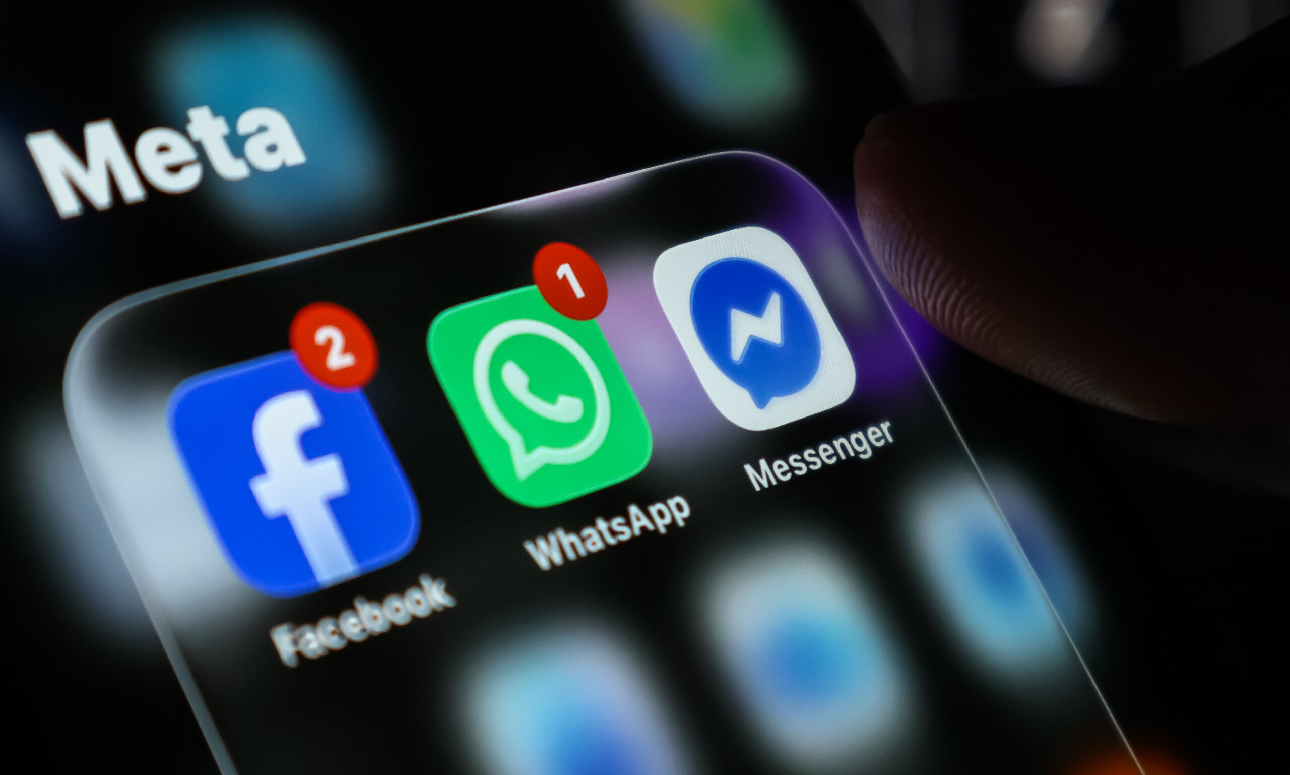 Closeup of a smartphone screen showing meta social media application icons including facebook, whatsapp, and messenger with notification badges